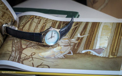 Armand Nicolet A740C light blue dial wristwatch with vertically brushed finish and blue leather strap laying on the book