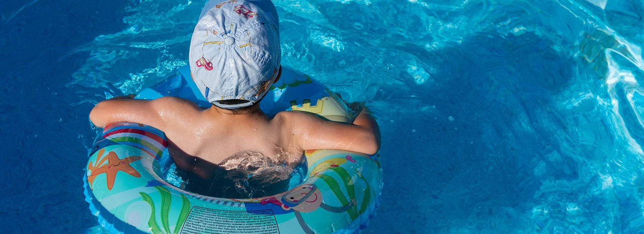 A child in a swim cap floating in a pool ring