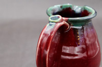 Ruby Red Pitcher with copper rim, roughly 6 inches wide (with handle) by 6.5 inches tall, (SK7857)