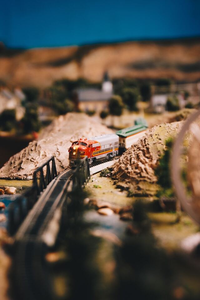 A model train about to cross a model bridge, surrounded by natural scenery