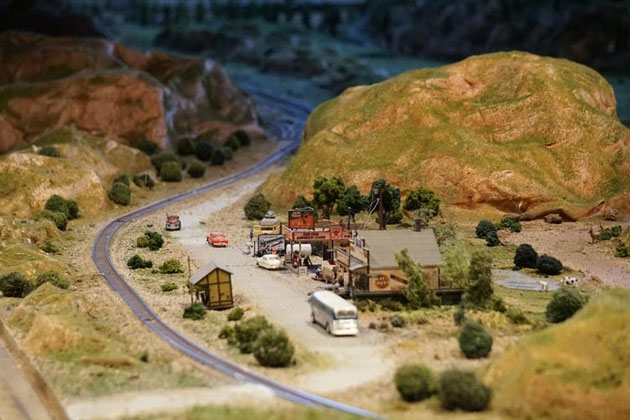 tiny model rest stop in hills with tracks passing by