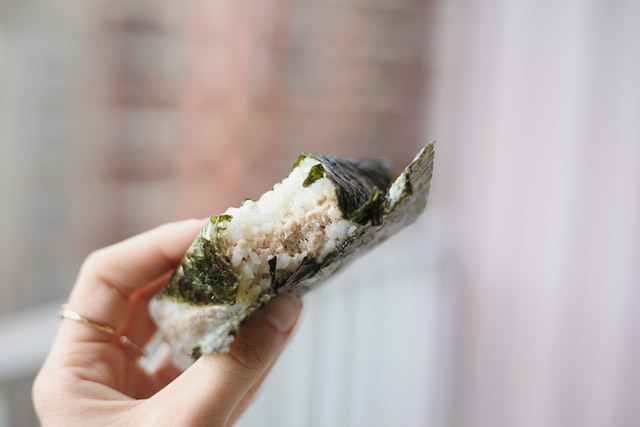 hand holding up a bitten onigiri