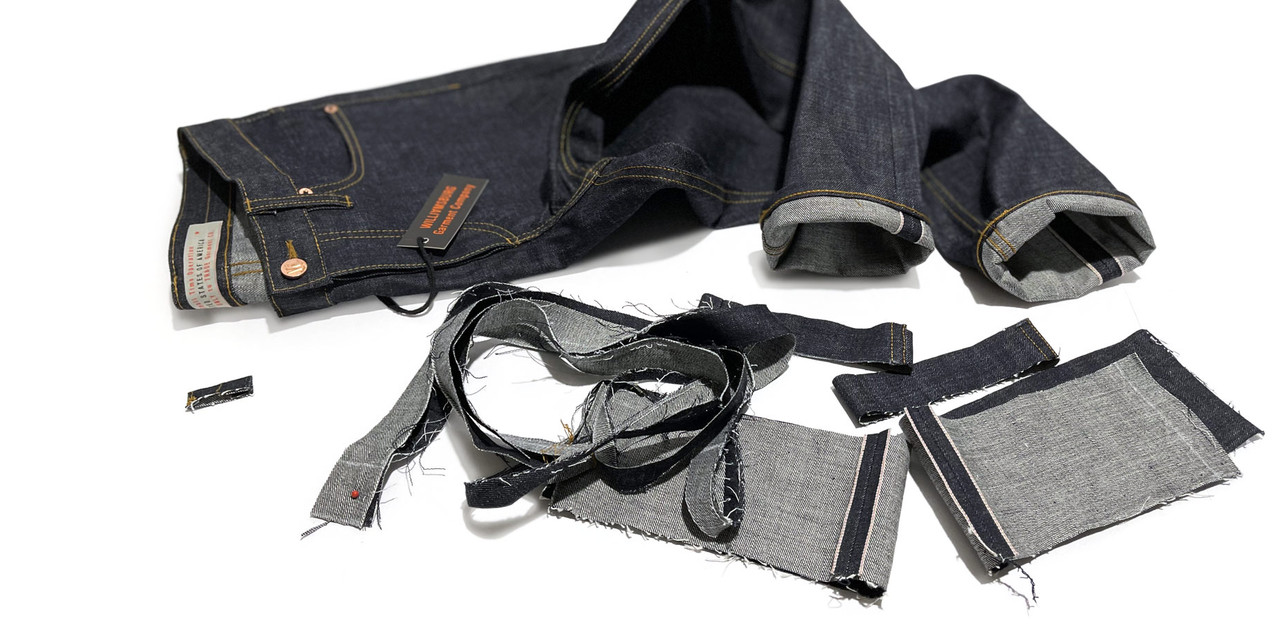 An example of the expert denim tailoring by Williamsburg Garment Company features tapered jeans with scraps in the foreground, showcasing a pair of the brand's American-made selvedge raw jeans.