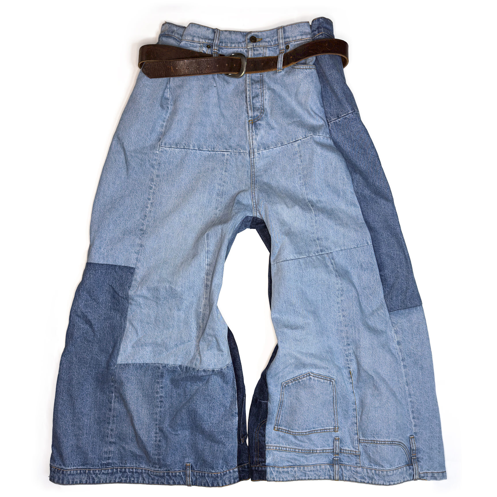 Front view of A.W.A.K.E. Mode patchwork jeans after professional shortening by Williamsburg Garment Company, showing the preserved inverted waistband hem and multi-shade denim paneling.