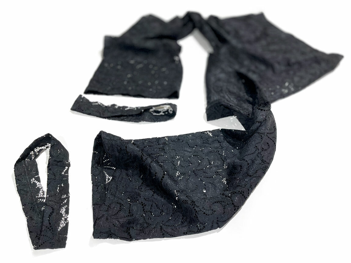 A pair of women's black lace pants, hemmed by stretch garment alterations service expert Williamsburg Garment Company, is displayed against a white backdrop.