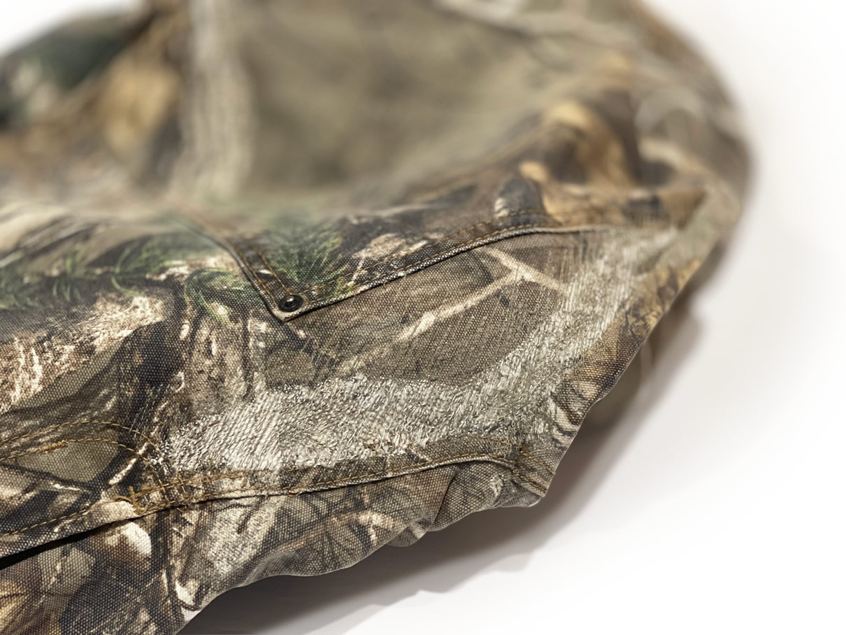 A close-up of the sewing repair detail of a large rip on the crotch of a pair of Mintcrew carpenter pants in real tree camouflage.