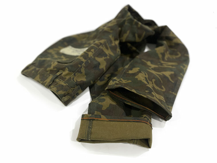 A hem of a pair of camo pants with orange custom colored chain stitch fulfills the specific request of a customer at Williamsburg Garment Company's hemming service.