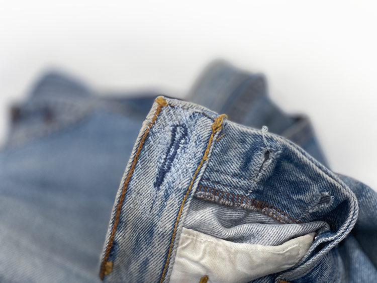 Inside view of jeans waistband features Williamsburg Garment Company's alterations service to mend and repair damaged keyholes (buttonholes) on denim jeans.