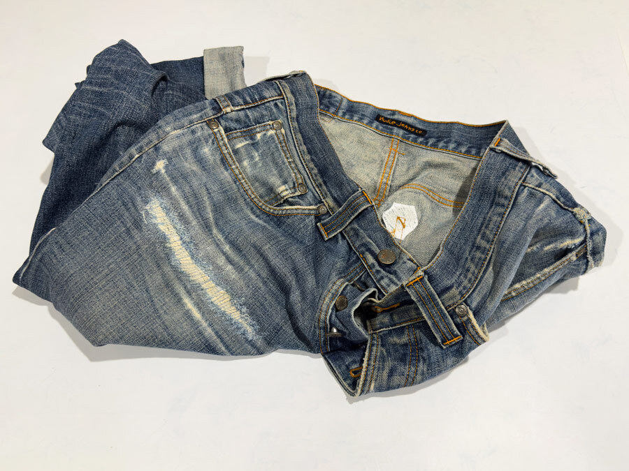 Close-up of Nudie jeans repaired by Williamsburg Garment Company, showing a large torn whisker area on the leg restored with expert denim repair.