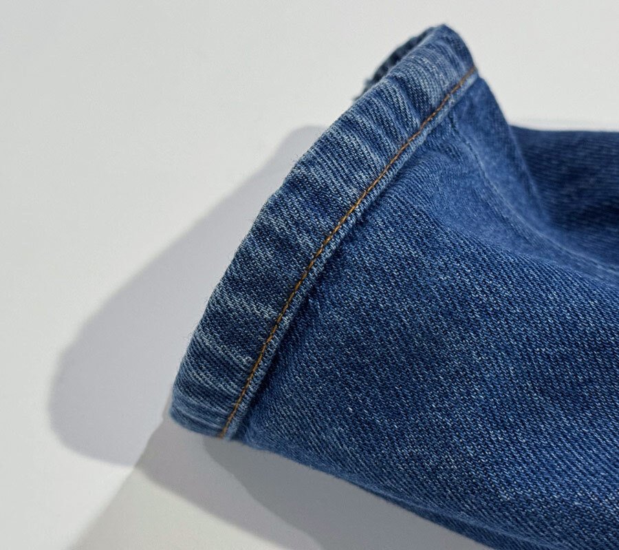 Close-up of jeans hem showing horizontal seam line created by original hem alteration