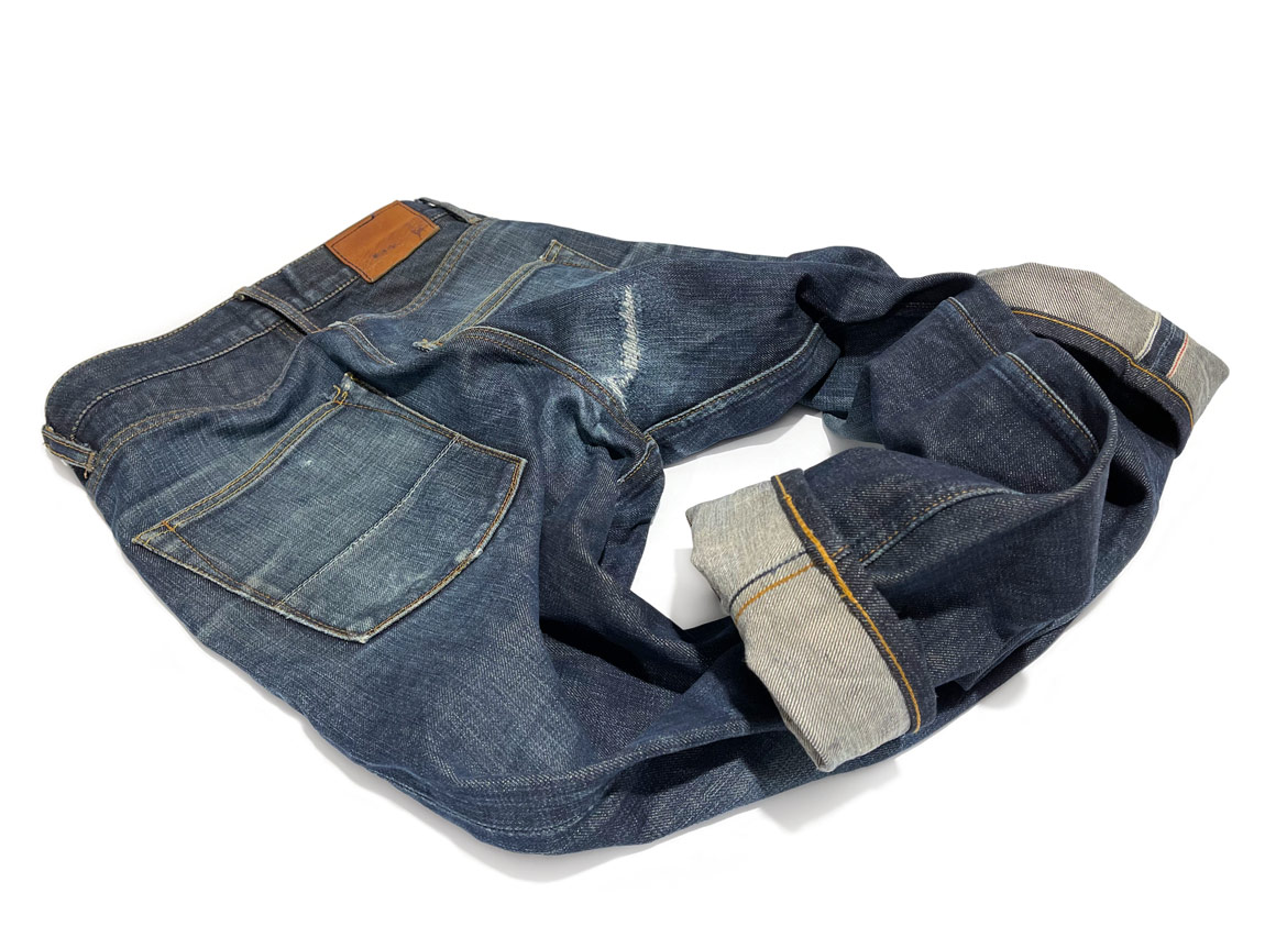 A pair of crotch repaired blue jeans with chainstitch hemming to shorten the inseam length