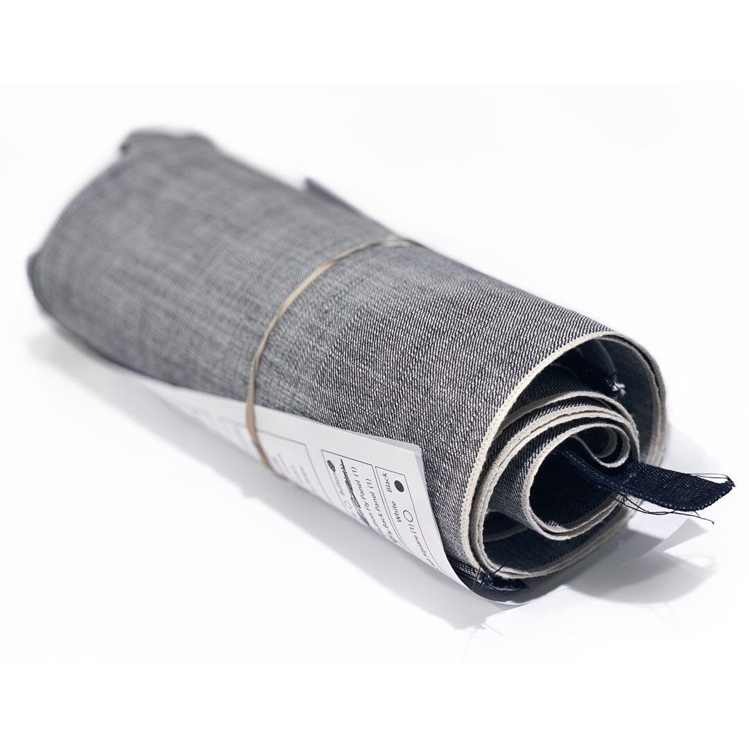 Selvedge denim fabric pattern parts used to assemble a pair of jeans are rolled together with an assembly detail sheet.