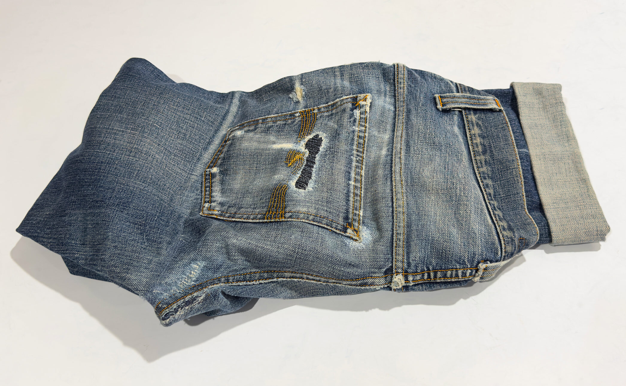 Nudie jeans repaired by Williamsburg Garment Company with visible repairs on the back pocket and seat using reinforced stitching and denim patching.
