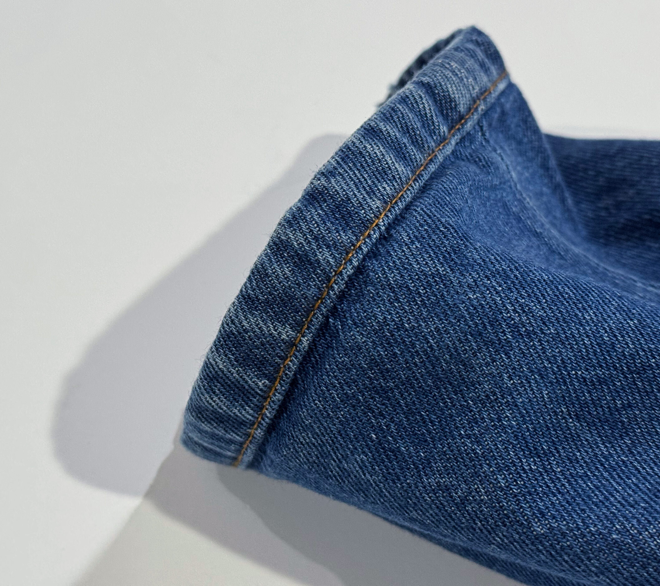 Close-up of jeans hem showing horizontal seam line created by original hem alteration.