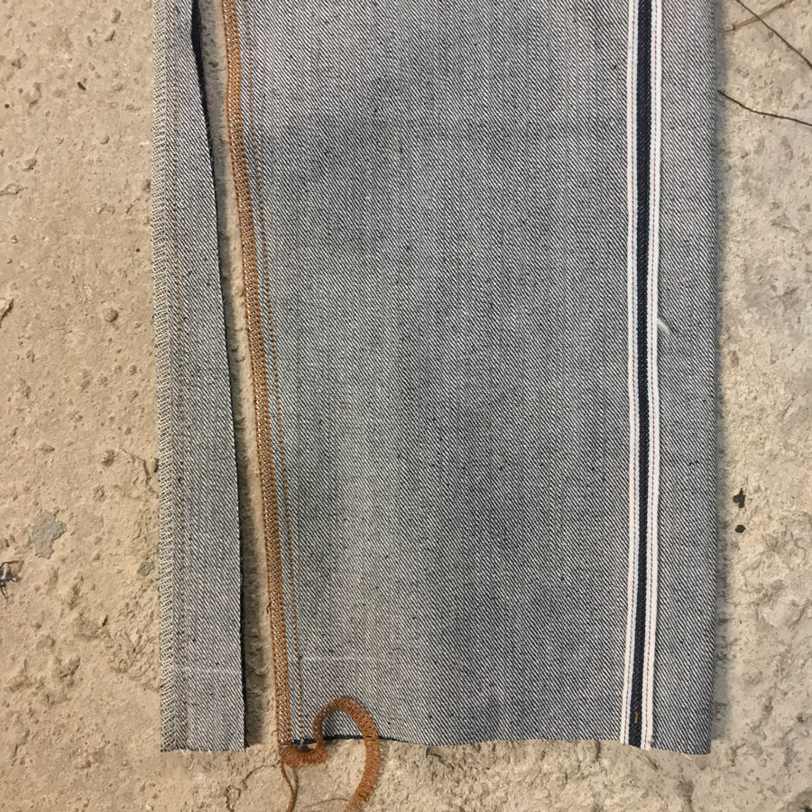 Overlocked hem of selvedge jeans with decreased leg opening