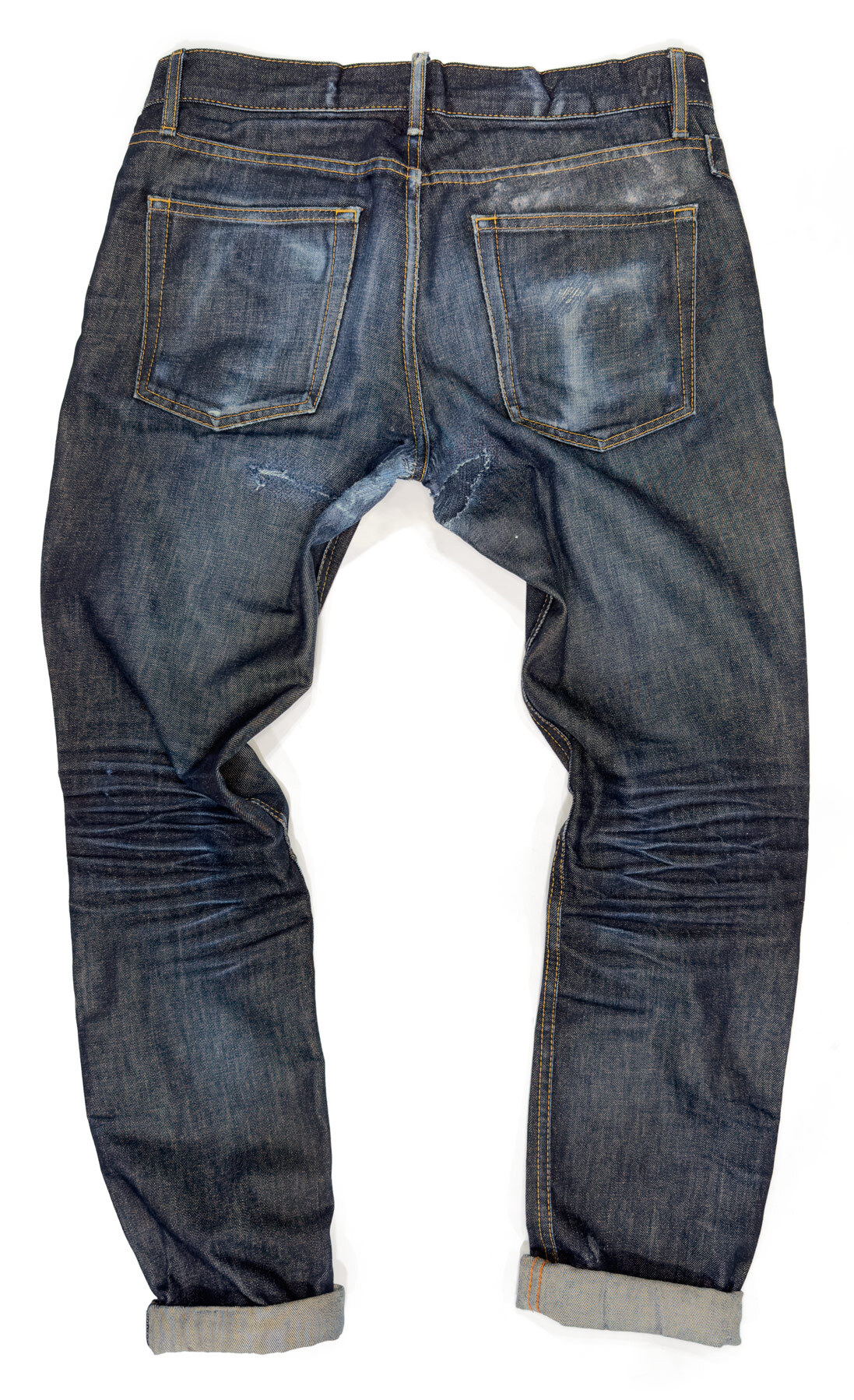 This is a rear view of a pair of vintage Williamsburg jeans, crafted from Cone Mills White Oak American-made fabric by Williamsburg Garment Company. The jeans, over six years old at the time of photographing, have received a patched fix for a crotch blowout, denim repair of small rips and holes, and features naturally formed raw denim fades.