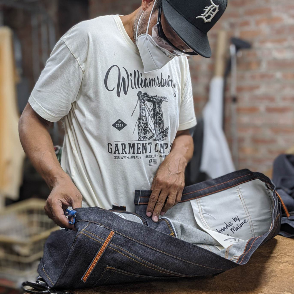 African American denim designer & brand owner Maurice Malone inspects handmade jeans.