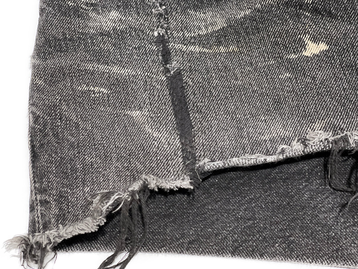 Close-up of repaired rip on cut-off denim shorts hem