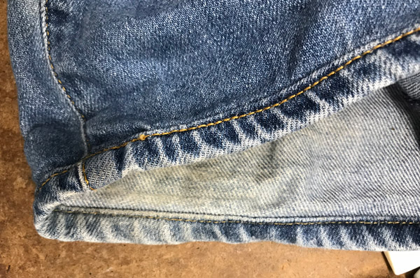 Close-up of original hem alteration on a pair of blue jeans