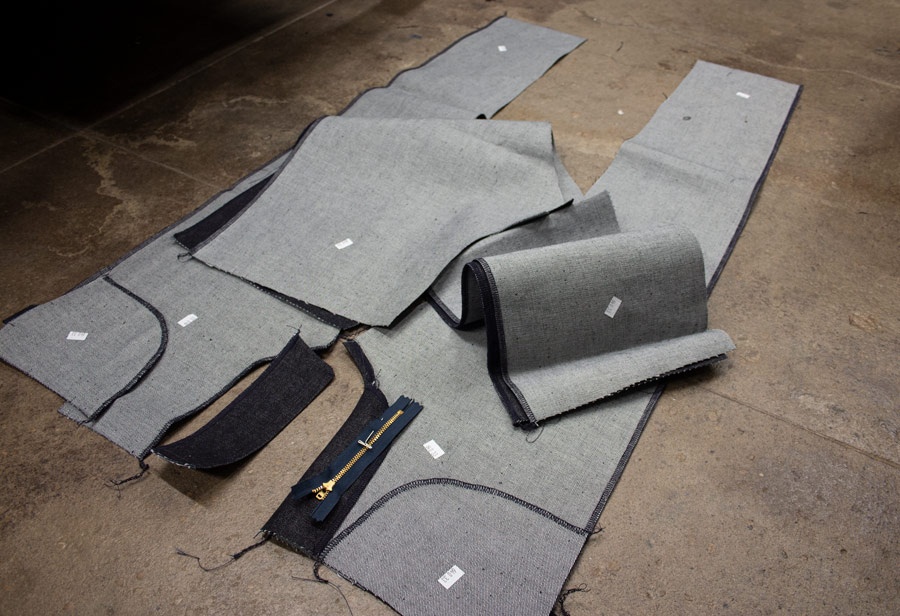 Custom jeans parts sewn with 4-thread overlock machine displayed on the floor.