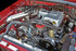 Scram Speed 79-93 SBF 5.0 302 Mustang Underdrive Power Steering Serpentine Pulley, installed in a car engine bay with visible belts and metal components. Scram Speed 79-93 SBF 5.0 302 Mustang Underdrive Power Steering Serpentine Pulley, installed in a car engine bay with visible belts and metal components.