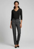 A woman wearing a black top and grey classic pants, standing in a relaxed pose against a neutral background.