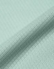 A close-up of a light mint green jacquard knit fabric with a textured pattern. The material appears soft and sustainable.