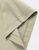 A close-up of a light green premium cotton short-sleeve tee shirt with a stitched hem and sleeve detail.