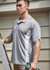 A men's short sleeve polo in grey with white side panels, featuring a logo on the sleeve.