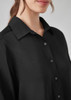 A black long sleeve shirt with a collared neckline and button detailing, featuring a close-up of the fabric texture.