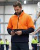 A Hi-Vis polar fleece full zip jacket in bright orange and navy, worn by a man using a phone.