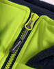 A close-up of a bright yellow zipper on a hooded puffer vest with a navy fleece lining. It has a branding logo.