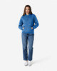 A blue hooded sweatshirt paired with jeans, featuring a front pocket and drawstring hood, modelled by a woman.