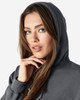 A dark grey hooded sweatshirt is displayed, featuring a model with long hair and a subtle smile.