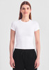 A white baby tee with short sleeves, paired with black trousers. The model stands against a neutral background.