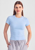 A light blue women's baby tee, featuring short sleeves and a fitted design, worn with grey joggers.