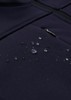 A dark navy softshell jacket with water droplets beading on the fabric, featuring a zippered pocket.
