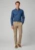 A man wearing a blue shirt and beige chinos, standing against a neutral background. The pants have a branding logo.