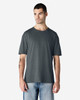 A man wearing a dark grey Gildan Softstyle adult T-shirt, paired with light blue jeans. The t-shirt has a logo.
