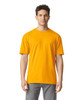 A person stands wearing a bright orange Gildan Softstyle adult T-shirt, paired with grey jeans. The shirt has a logo.