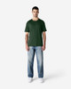 A green Gildan Softstyle adult T-shirt displayed on a model, paired with blue jeans and white shoes.