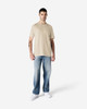 A light beige Gildan Softstyle adult T-shirt displayed on a model, paired with blue jeans. The model stands on a plain background.