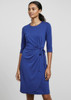 A blue women's dress features three-quarter sleeves and a tied waist detail, set against a neutral background. It has branding.