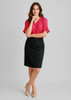 A woman stands in a fitted black skirt paired with a pink blouse, wearing nude heels, and posing against a neutral background.