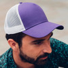 A purple and white trucker cap with a mesh back, featuring a solid front panel.