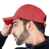 A red cap viewed from the side, featuring a curved brim and an adjustable strap at the back.