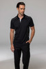 A black polo shirt with contrasting white accents, modelled by a man wearing black trousers. The shirt features a logo.