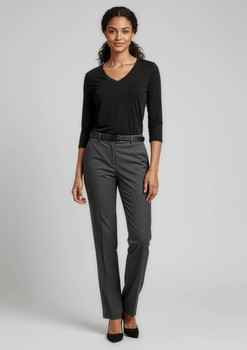 A woman wearing a black top and grey classic pants, standing in a relaxed pose against a neutral background.
