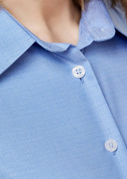 A close-up of a light blue button-up shirt featuring a collar and two buttons. The shirt has a logo.
