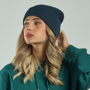 A navy blue beanie is worn by a person with long, wavy hair, set against a light background.